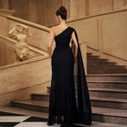 Back view of black one-shoulder evening gown with beaded detail and long tulle drape