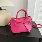 Rose pink bow-trimmed small square handbag with bow front and crossbody strap
