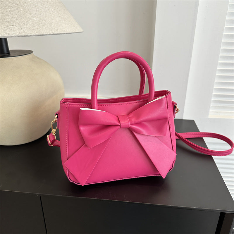 Rose pink bow-trimmed small square handbag with bow front and crossbody strap