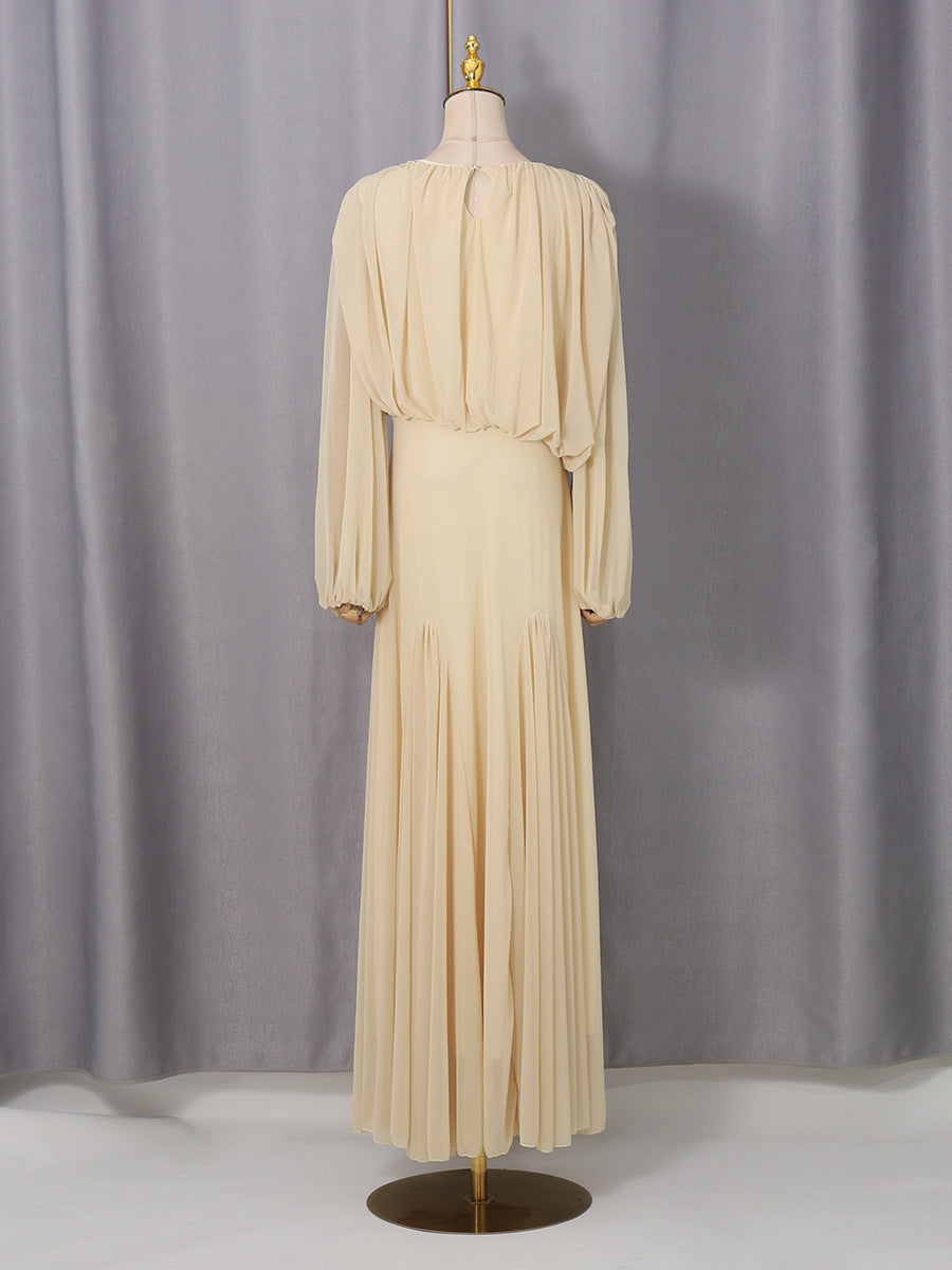 Cream pleated maxi dress with long sleeves, round neckline, and gathered waist