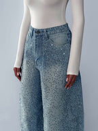 High-waist blue jeans with belt loops and irregular rhinestones on the waistband