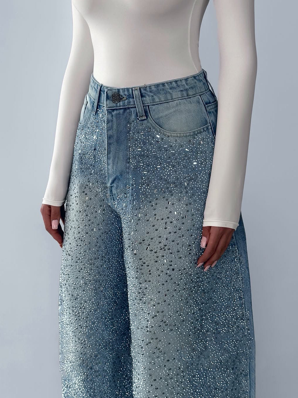 High-waist blue jeans with belt loops and irregular rhinestones on the waistband