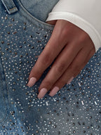 Blue denim jeans with irregular rhinestone embellishment across the front
