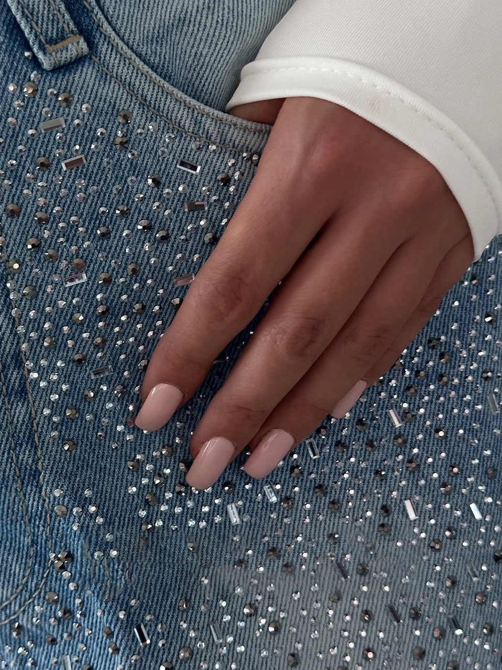 Blue denim jeans with irregular rhinestone embellishment across the front