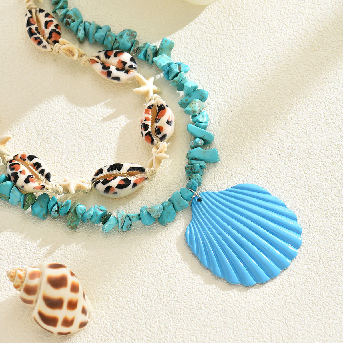 Turquoise rope necklace with conch shells, starfish, and a blue scallop shell charm
