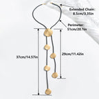 Gold disc tassel necklace on black cord with round metal pendants and extender