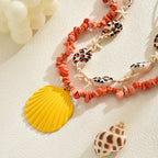 Orange rope necklace with conch shell beads, starfish, and a yellow scallop shell charm