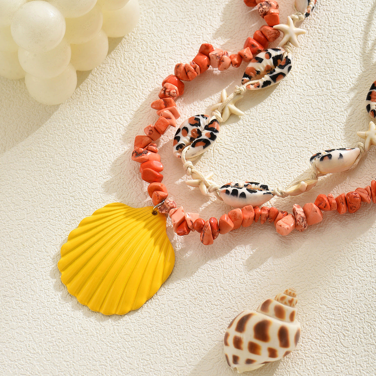 Orange rope necklace with conch shell beads, starfish, and a yellow scallop shell charm