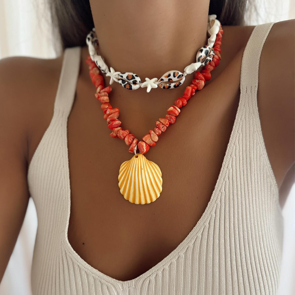 Orange conch rope necklace with starfish charms and yellow scallop shell pendant on neckline