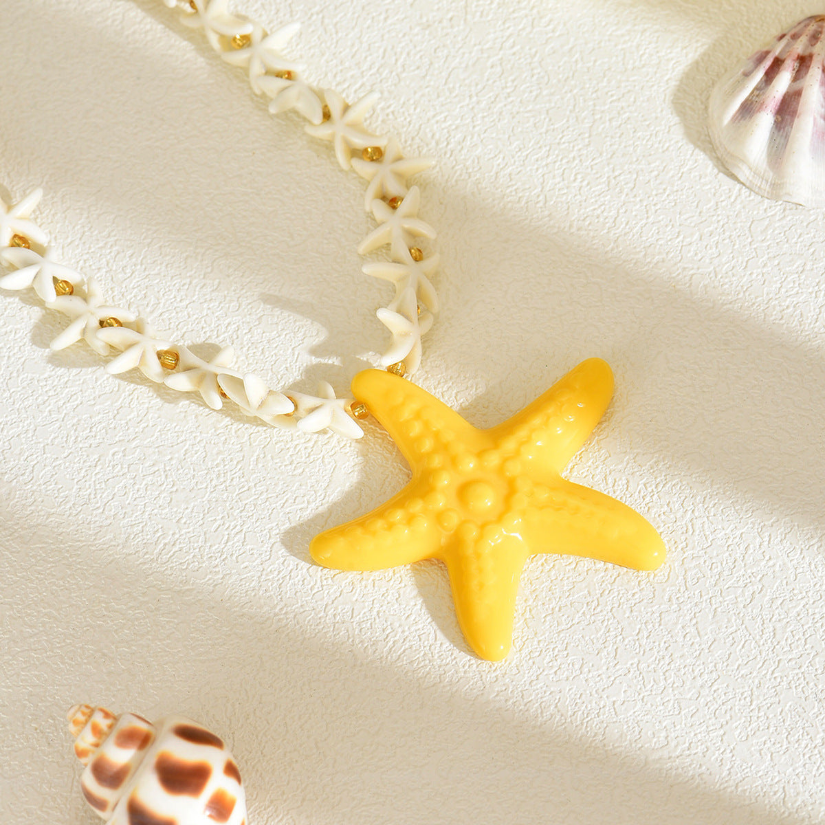 Yellow starfish pendant on white star-link necklace with gold accents