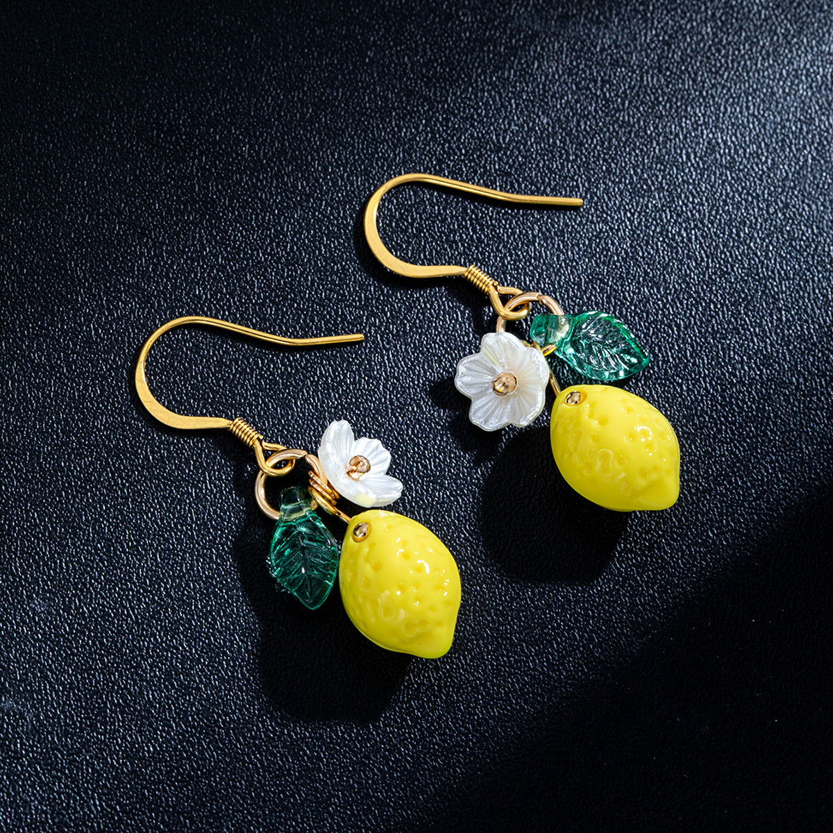 Pair of lemon drop earrings with yellow lemon charms, green leaves, and white floral accents
