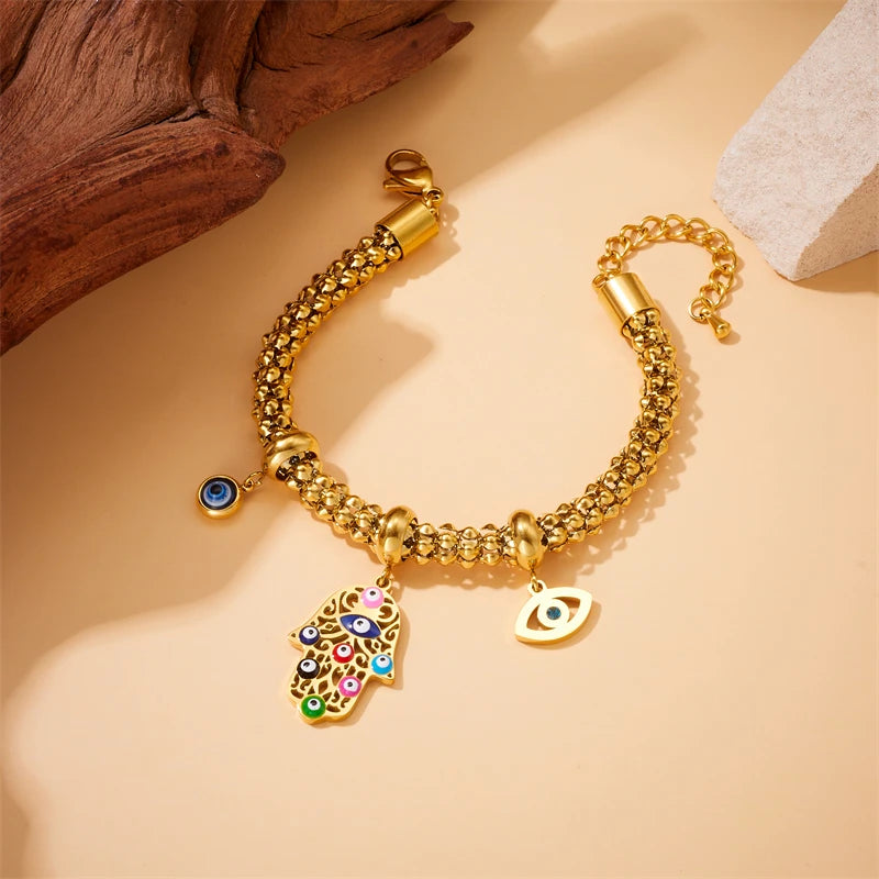 Gold-tone beaded charm bracelet with blue eye charms and hamsa hand pendant