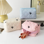 Quilted cosmetic bags in light blue, cream, and pink with bow embroidery and zips