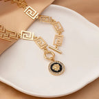 Gold embossed chain anklet with Greek-key panel links and round lion medallion charm