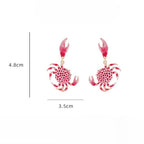 Crab drop earrings with red-and-white dotted bodies, pink claws, and gold hooks