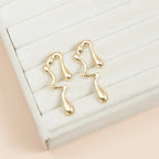 Gold-tone lava drip drop earrings on white display pad