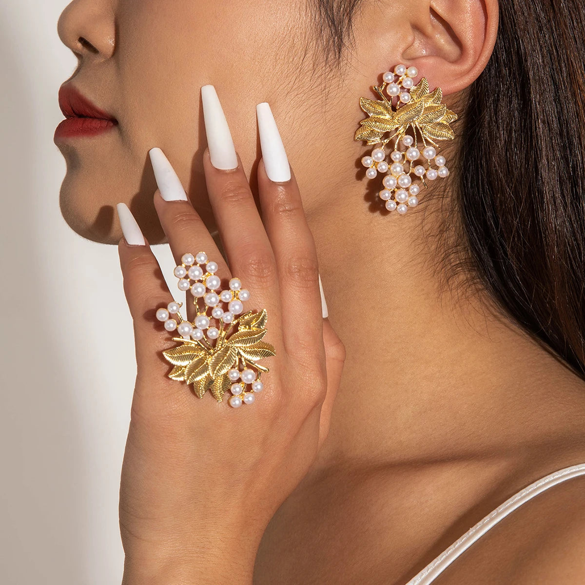 Pearl cluster drop earrings with gold-tone leaf accents, worn on ear