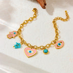 Gold-tone charm bracelet with evil eye heart, hamsa hand, and turquoise bead accents
