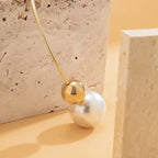 Gold-tone necklace with a white pearl bead and round gold charm on a thin chain