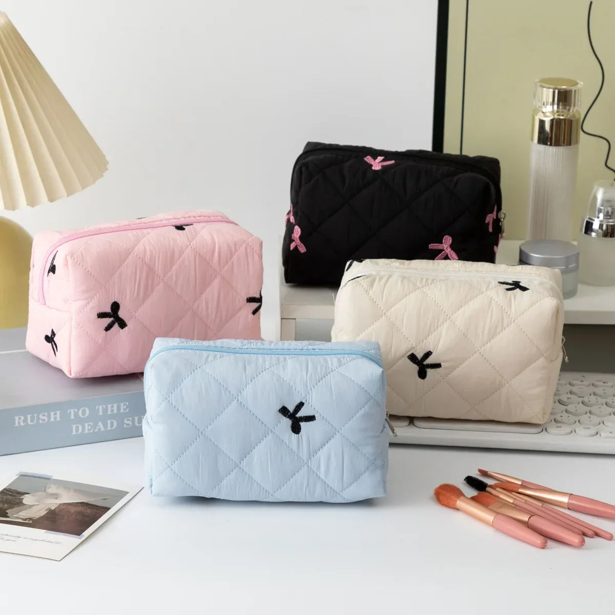 Quilted cosmetic bags in pink, black, white, and light blue with bow embroidery