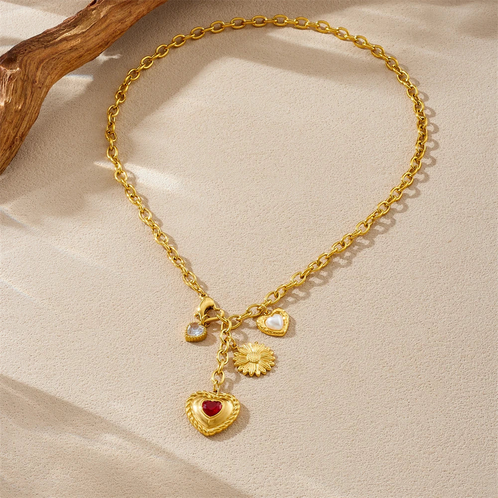 Gold tone chain pendant necklace with red heart charm, white pearl hearts, and flower charm
