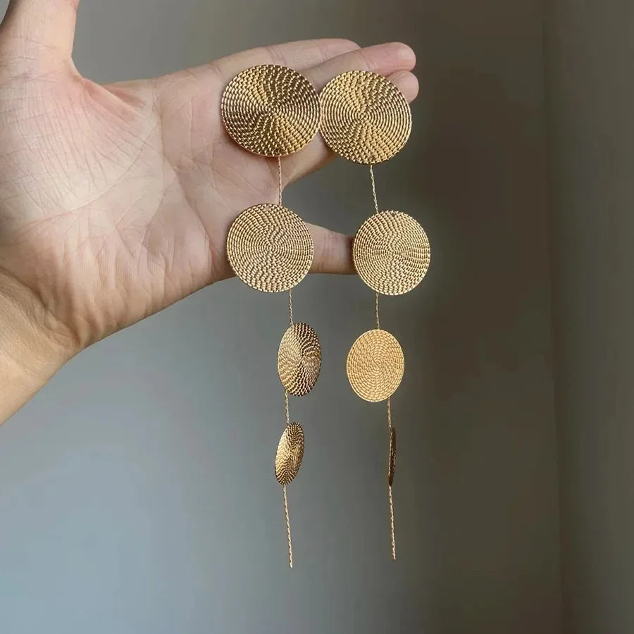 Gold-tone woven disc dangle earrings in hand, four circular drops with tassel tails