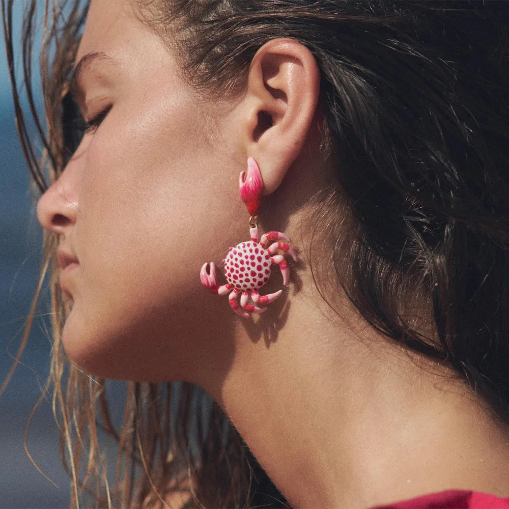 Worn crab enamel earrings with red-and-white dotted crab and pink claws on gold hooks