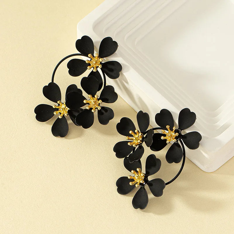 Black camellia-style flower dangle earrings with gold-tone star centers and hoop drops