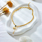 Gold lariat necklace with heart charms, blue bead, and pearl hanging detail