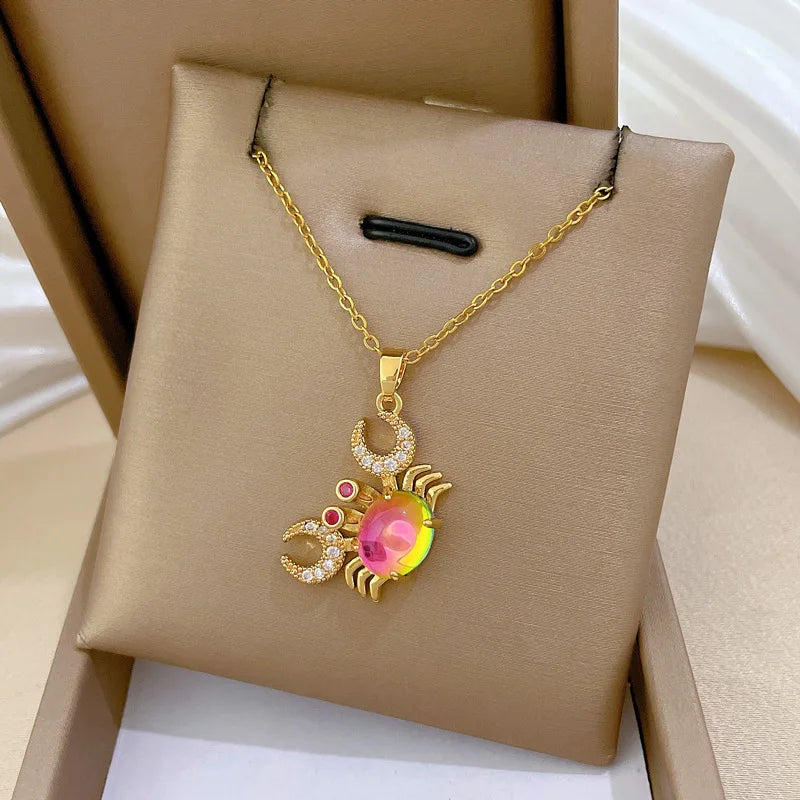 Gold-tone crab pendant necklace with pink center gemstone and red/clear rhinestones.