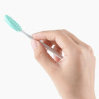 Teal silicone cleansing brush with white handle held in a hand