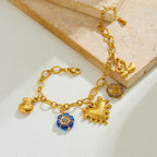 Gold-tone charm necklace with blue flower charm and heart-like pendant plus bow details
