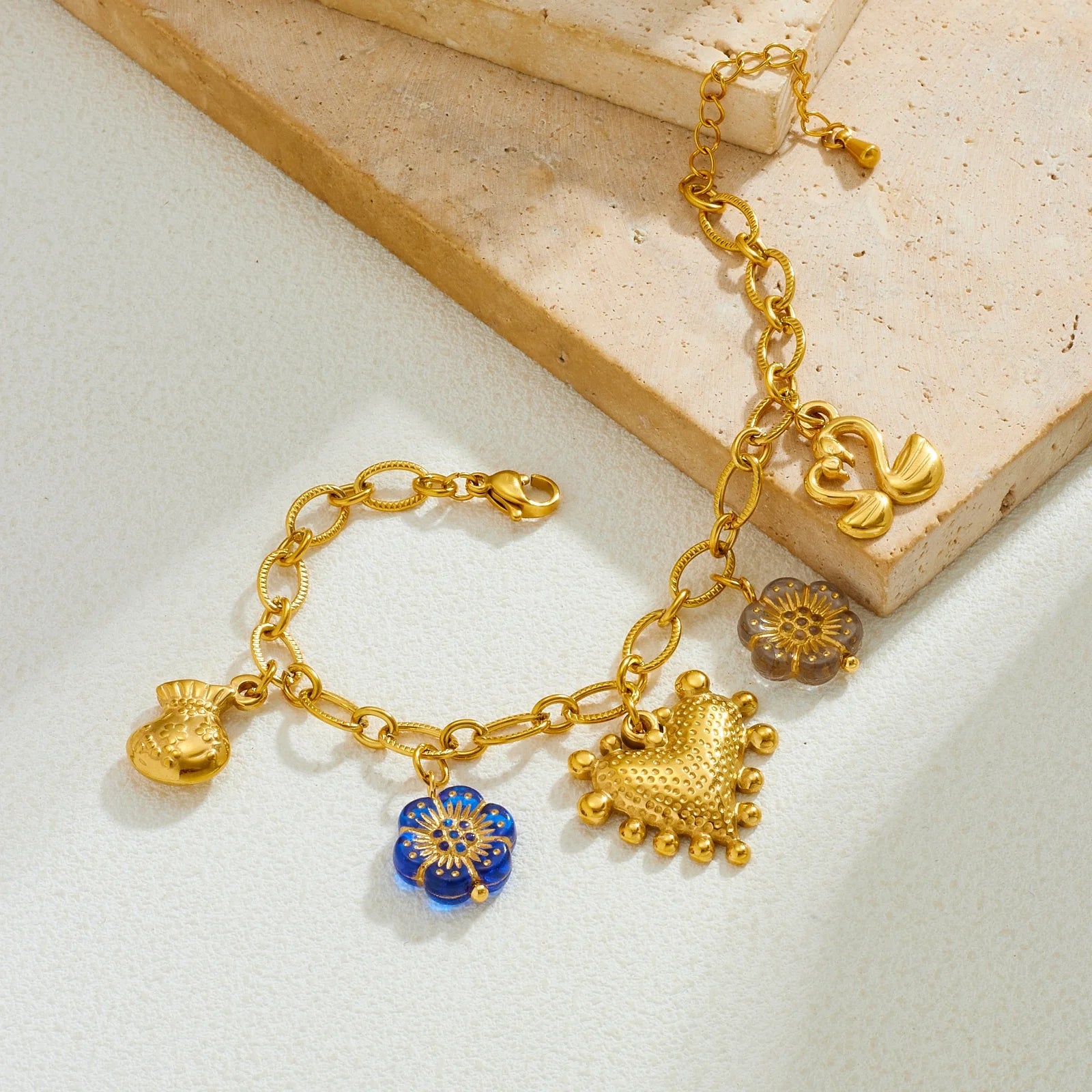 Gold-tone charm necklace with blue flower charm and heart-like pendant plus bow details