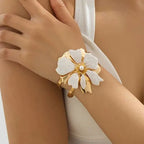 Flower cuff bangle bracelet with gold-tone frame and white enamel flower, pearl center.