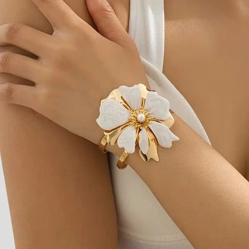 Flower cuff bangle bracelet with gold-tone frame and white enamel flower, pearl center.