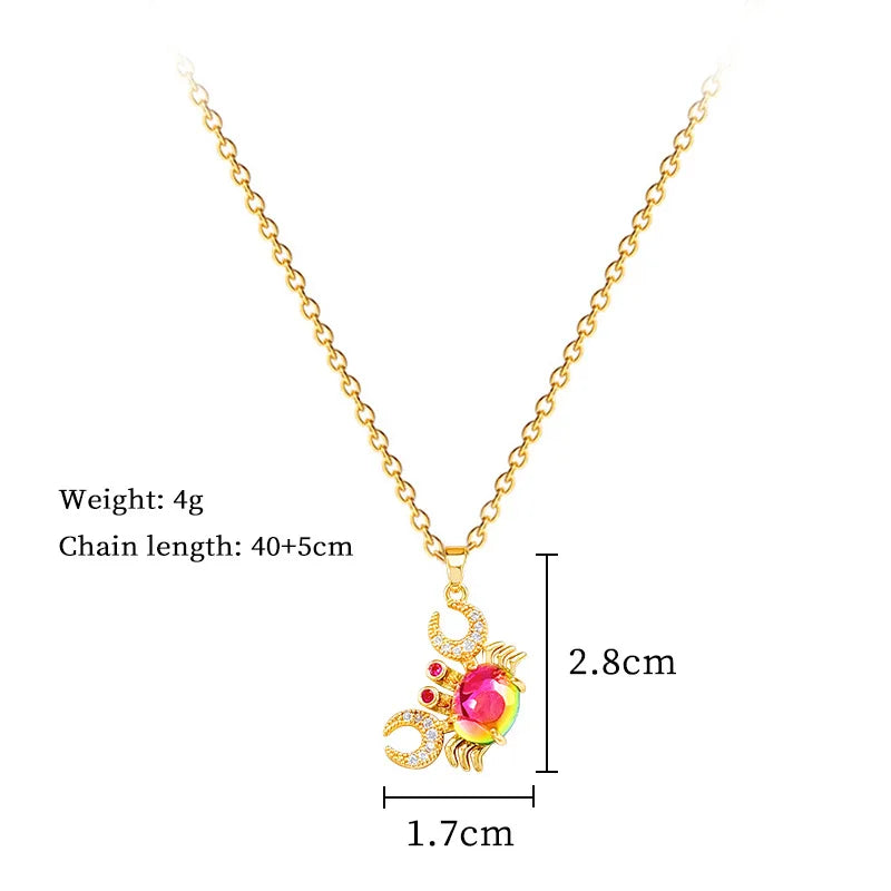 Gold-tone crab pendant necklace with pink center gemstone and sparkling red/clear accents.