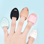 Assorted teardrop finger puff sponges on fingers: black, tan, pink, light blue, white.