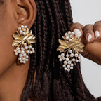 Pearl and gold-tone leaf cluster drop earrings on ear