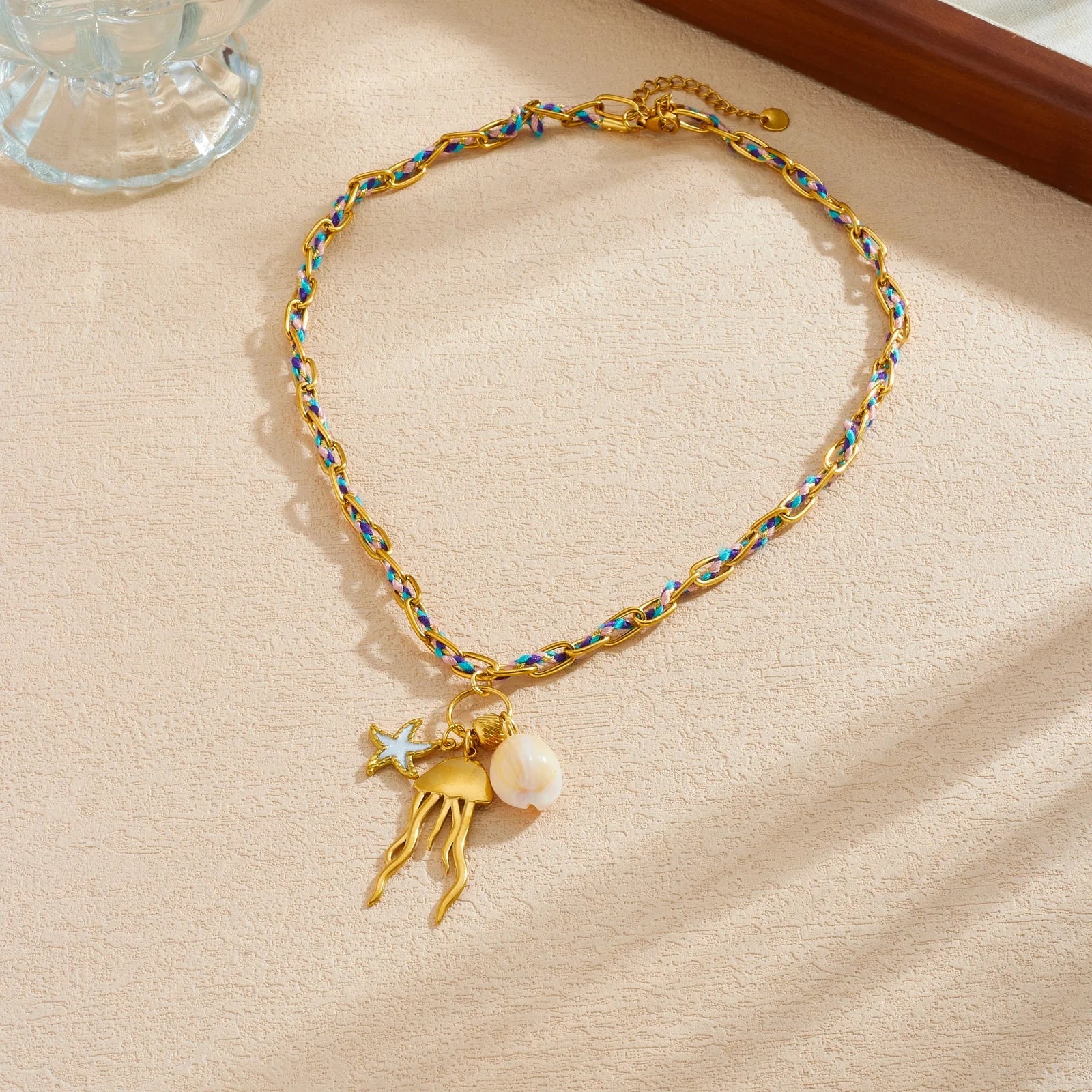 Jellyfish pendant necklace with gold starfish charm and white shell bead on blue gold chain