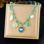 Turquoise beaded pendant necklace with sun-eye charm, moon disk, and pearl drops
