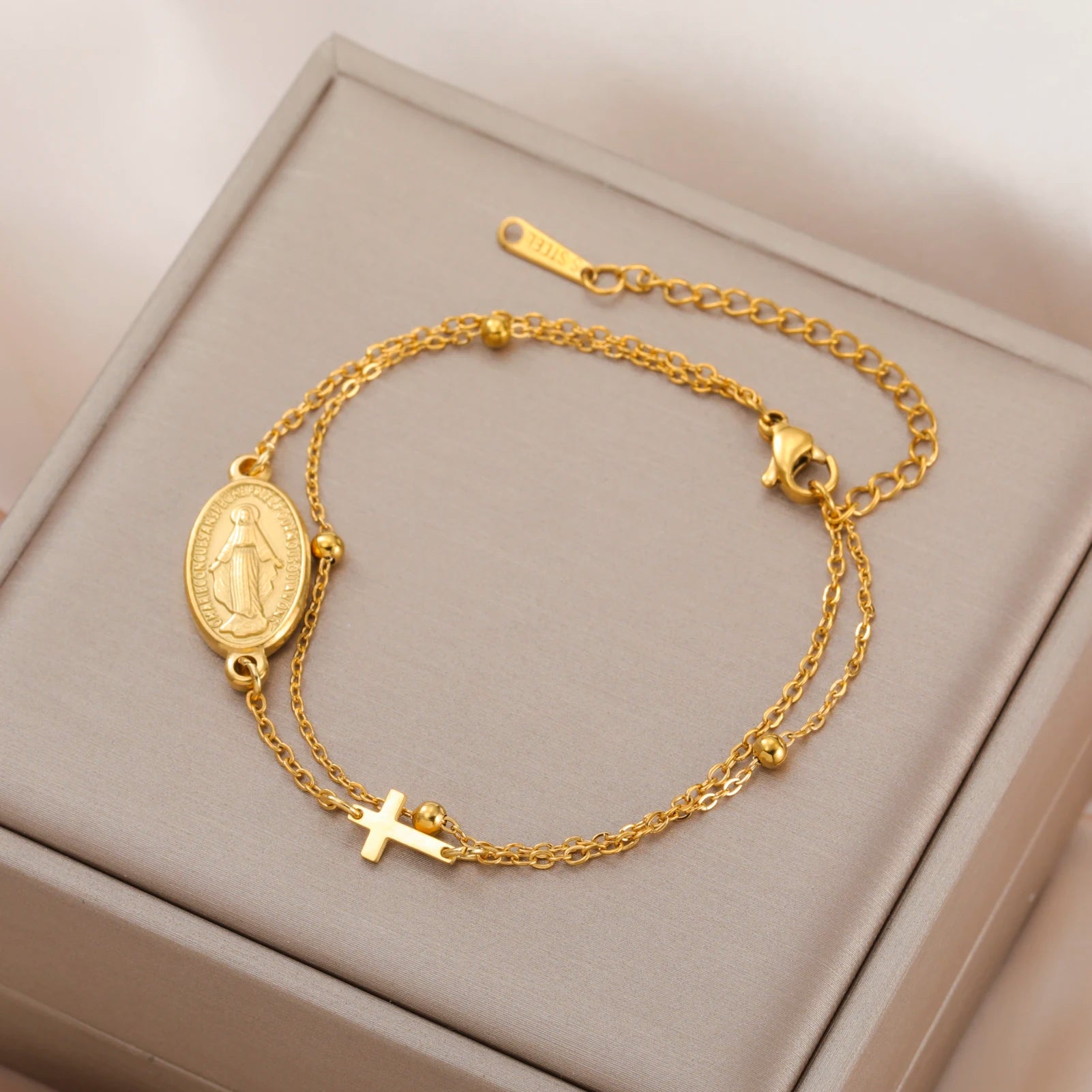 Gold-tone bracelet with oval Virgin Mary pendant, cross charm, and layered chain links