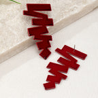 Geometric stud earrings in red with jagged zigzag shapes and a visible earring post