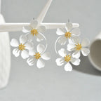 White camellia-style flower dangle earrings with gold-tone star centers and round hoop drops