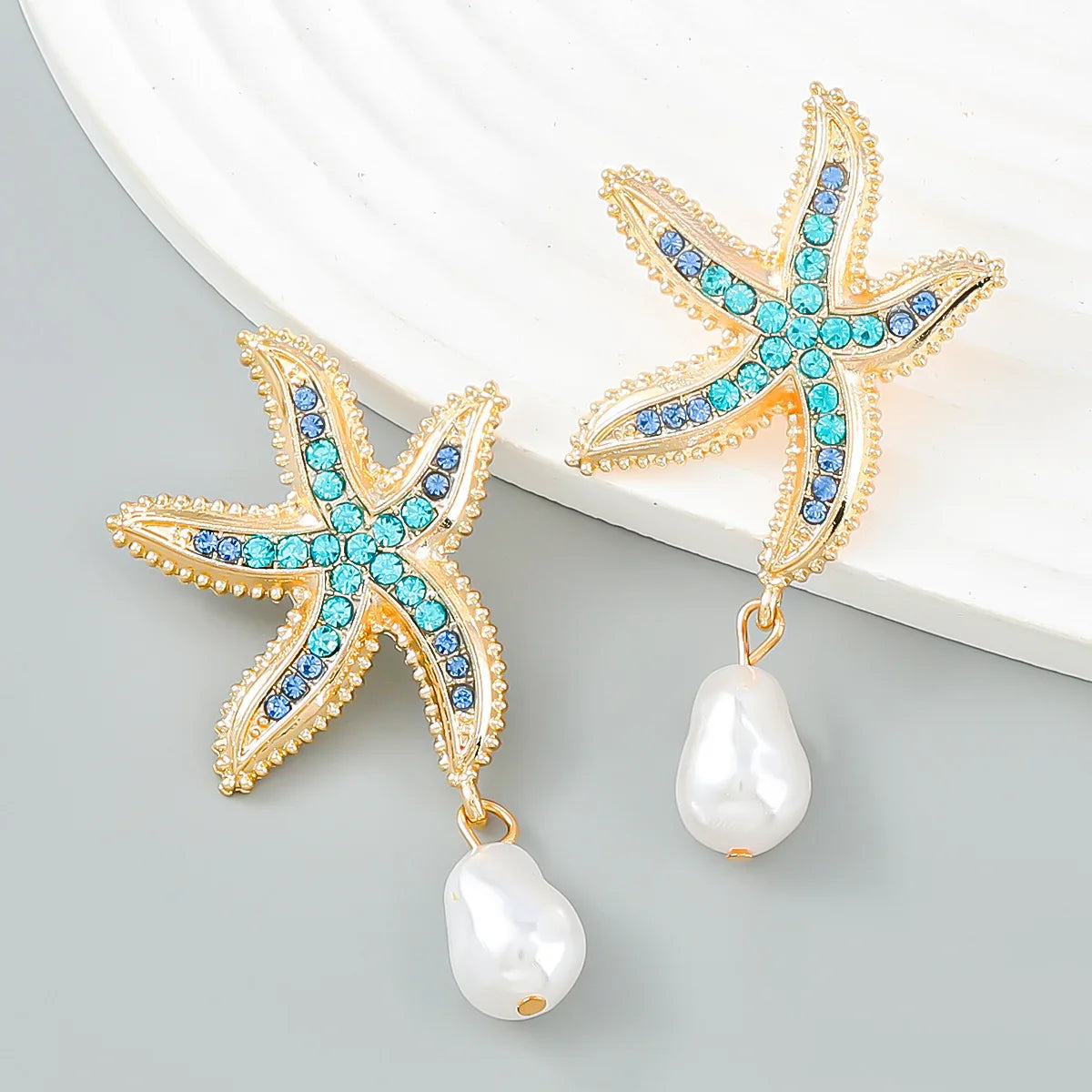 Gold-tone starfish earrings with blue/turquoise crystals and white pearl drop pendants
