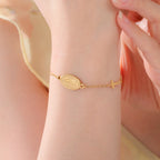 Gold-tone Virgin Mary bracelet with oval pendant and cross charm, worn on wrist
