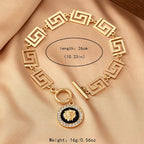 Gold embossed chain anklet with Greek-key links, round lion medallion, and ring clasp