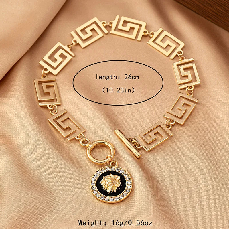 Gold embossed chain anklet with Greek-key links, round lion medallion, and ring clasp