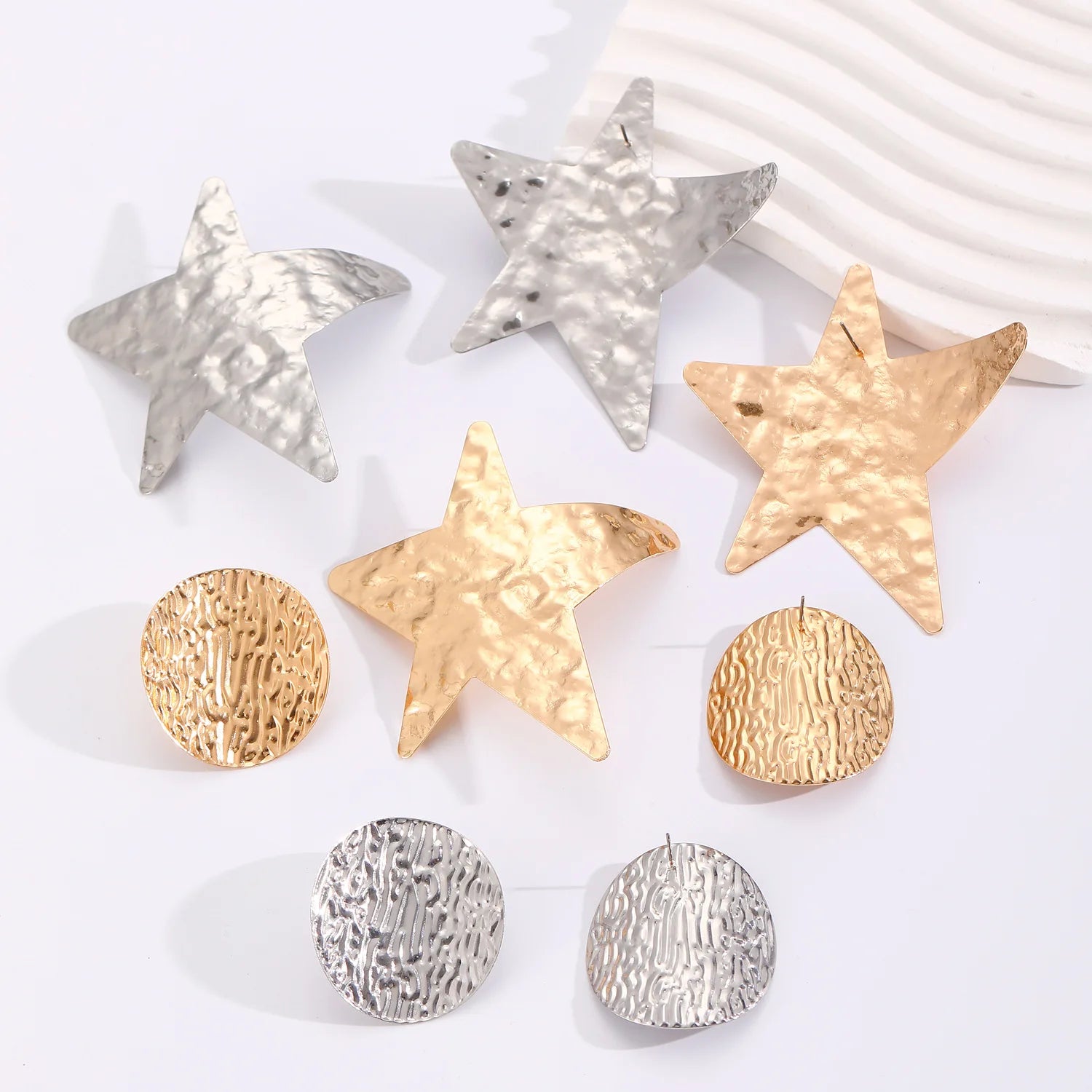 Assorted metal earrings with star and round stud shapes in gold and silver