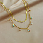 Gold-tone double-layer snake chain necklace with blue evil-eye charms and pearl details