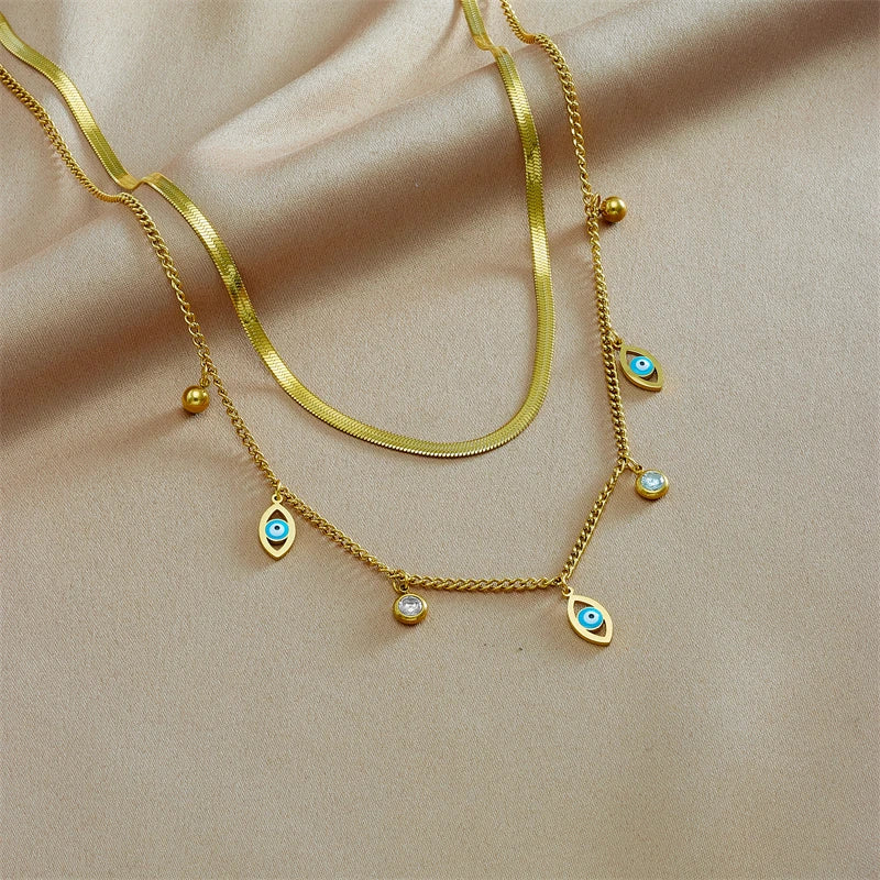 Gold-tone double-layer snake chain necklace with blue evil-eye charms and pearl details